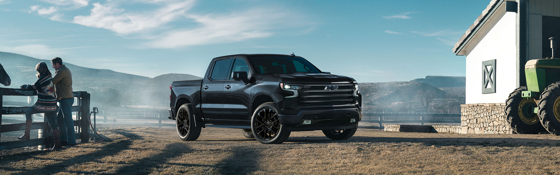 Black Chevrolet Silverado 1500 on a farm near a barn and tractor.
