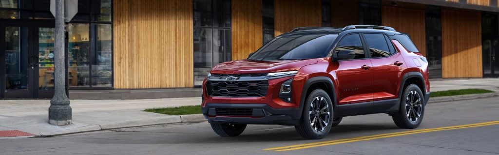 2025 Chevrolet Equinox in radiant red parked on a city street, highlighting its bold front grille, sleek design, and modern alloy wheels.